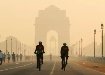 Men ride their bicycles along Kartavya Path in front of the smog-shrouded India Gate in New Delhi.