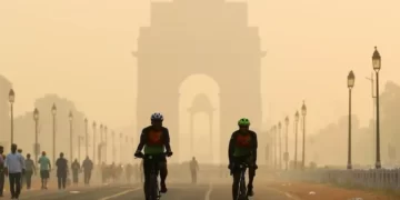 Men ride their bicycles along Kartavya Path in front of the smog-shrouded India Gate in New Delhi.